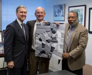 Secretary William Cohen and the Caribbean Baseball Initiative’s Lou Schwechheimer present a picture of Jackie Robinson to Dr. Lonnie Bunch, Director of the National Museum of African American History and Culture.